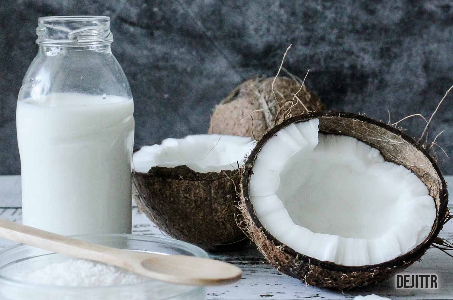 coconut split in two with a bottle filled with coconut milk