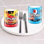 two tubs of g fuel on a plate with a knife and fork