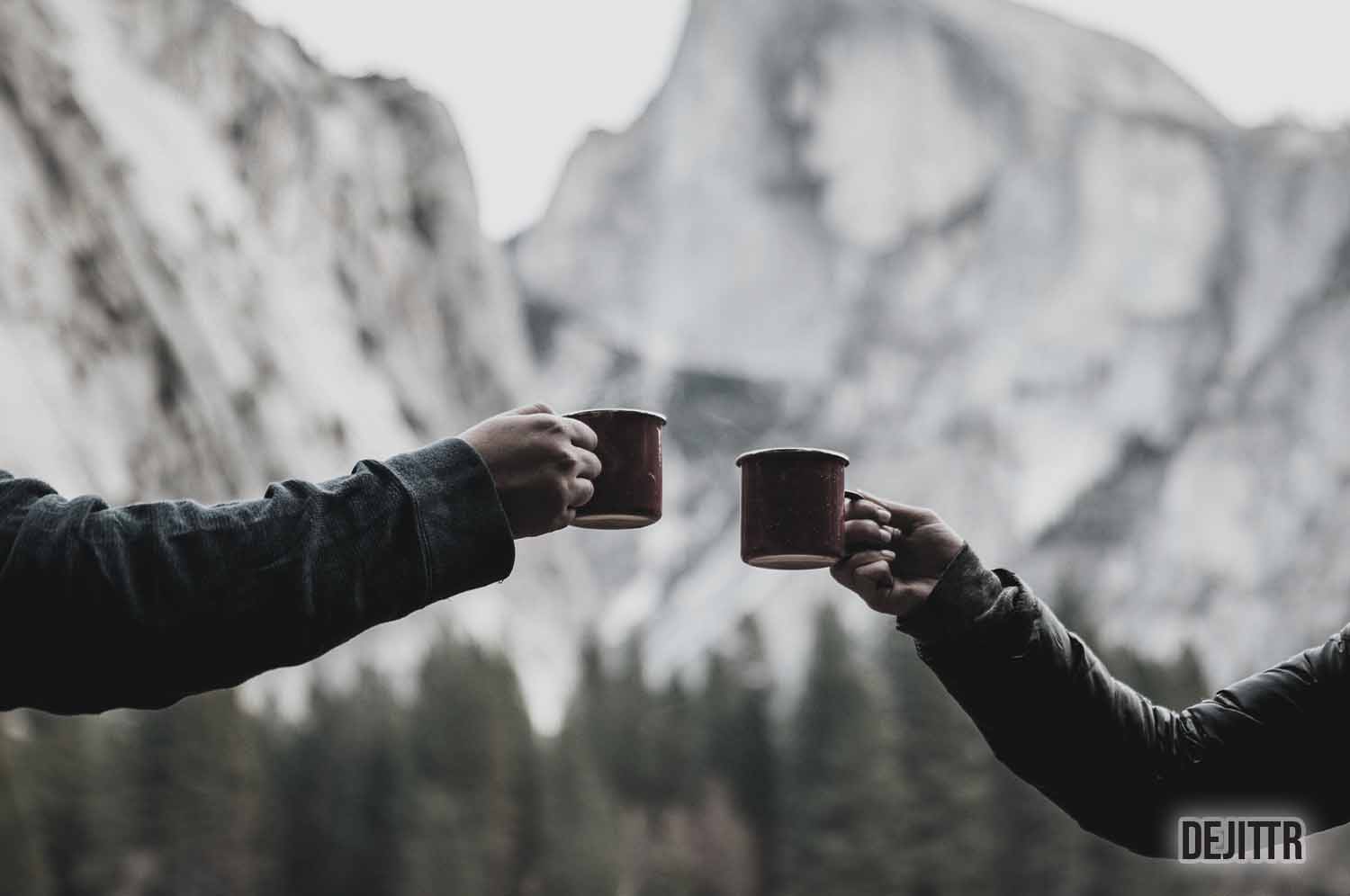 Two people holding cups of a hot beverage about to cheers