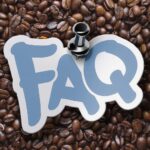 Thumb tack pinning FAQ sign on top of coffee beans background