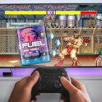 Person playing a fighting video game with a tub of g fuel as a player on the tv screen